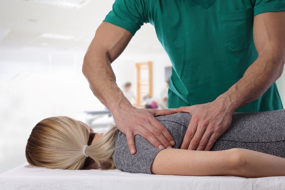 A practitioner's hands working on a patient's lower back.