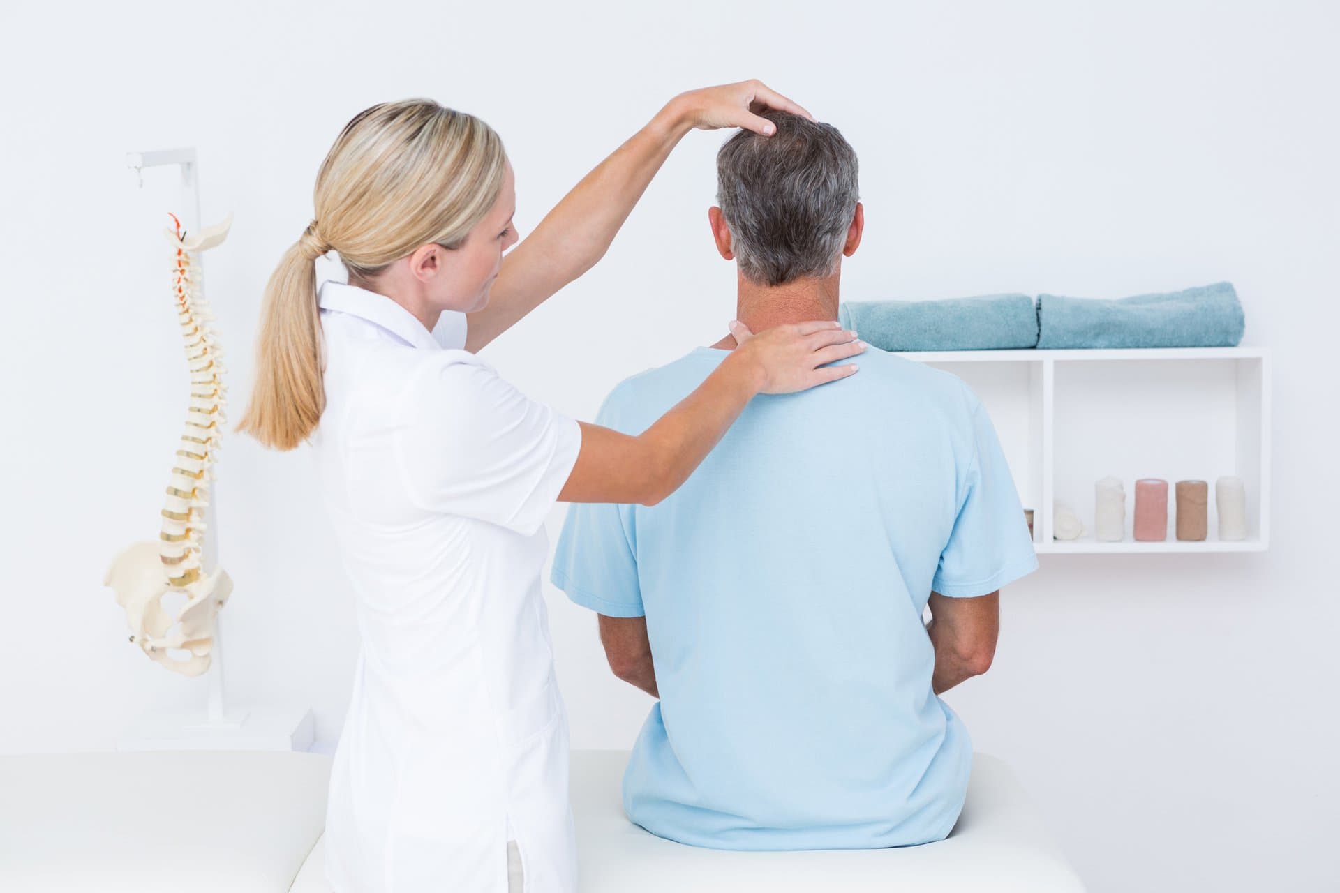 A practitioner assessing a seated patient's head and shoulder alignment.