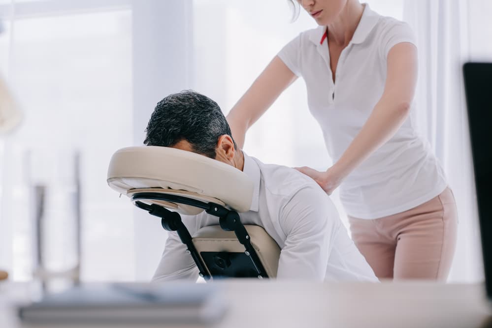 A seated chair massage being given through clothing.